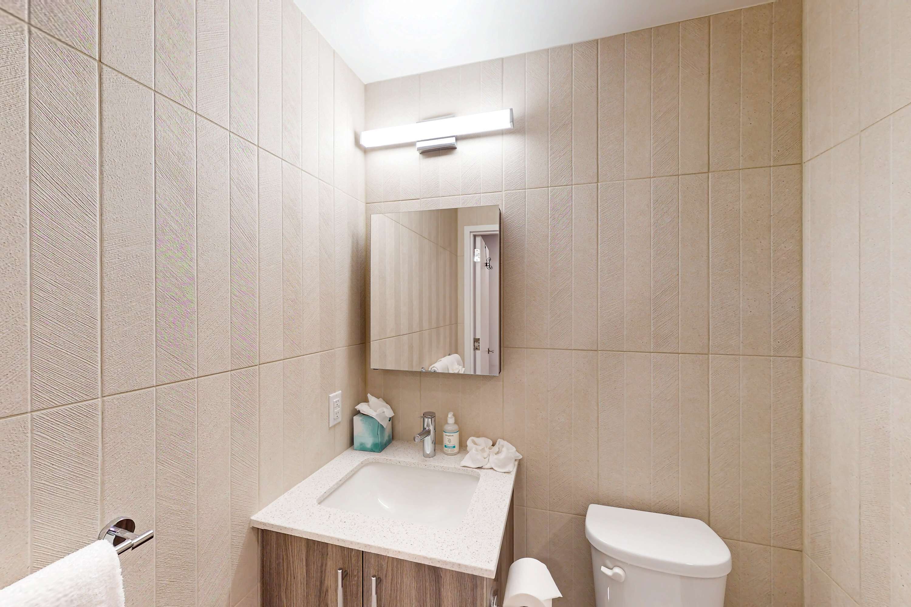 A bathroom with a sink, toilet, mirror, and towel rack.