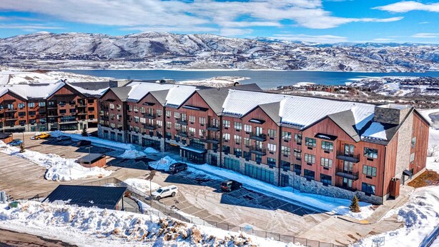 Ein mehrstöckiges Hotel mit modernem architektonischen Design, mit Parkplatz und Blick auf einen See und Berge im Hintergrund.