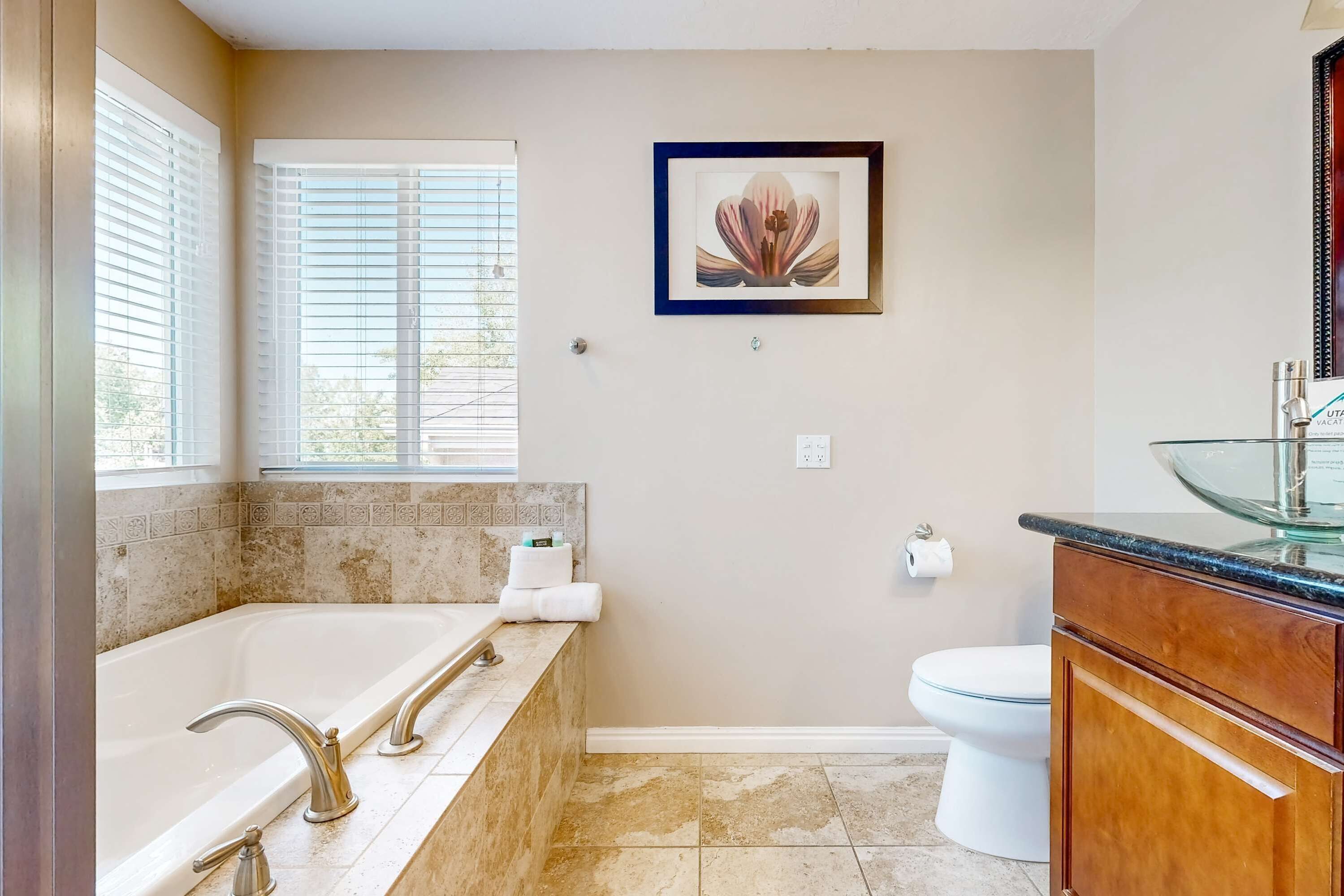 A bathroom with a bathtub, toilet, and a framed picture on the wall.
