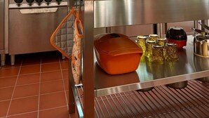 Een keuken met een fornuis, oven en een raam met uitzicht op groen.