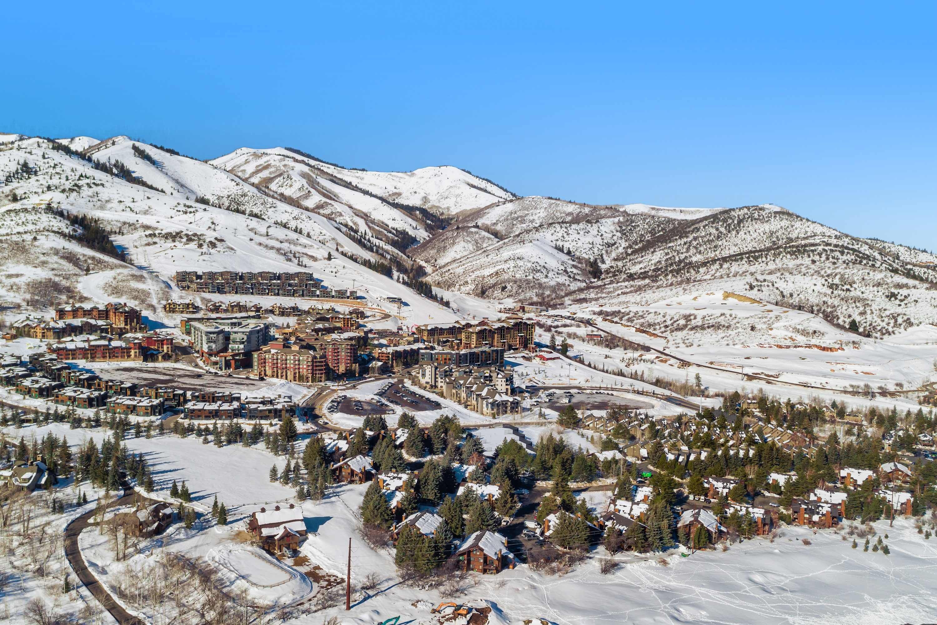 Un pueblo cubierto de nieve con una combinación de edificios residenciales y comerciales, incluyendo un hotel destacado con un telesilla visible al fondo.