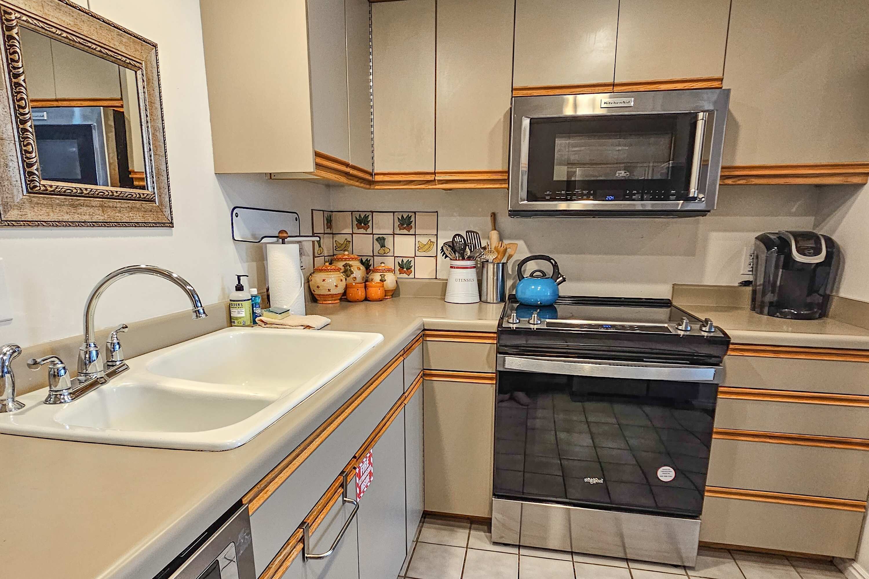 A kitchen with a sink, stove, microwave, and cabinets.