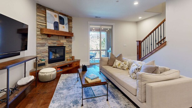 A living room with a stone fireplace, a flat-screen TV, a sofa, and a staircase. - Spacious townhouse with community pool, balcony & gym - close to Hideout (Hideout)