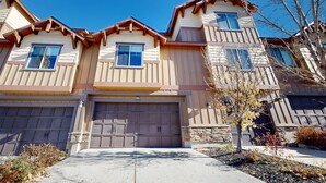 A multi-story residential building with a garage, a stone facade, and a clear blue sky. - Spacious townhouse with community pool, balcony & gym - close to Hideout (Hideout)