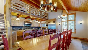 A spacious kitchen with wooden beams, a long dining table, and red chairs. - Beautiful ski chalet with gourmet kitchen, theater room & private hot tub (Brighton)