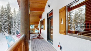 A wooden deck with a view of snow-covered trees, a hammock, and a flag. - Beautiful ski chalet with gourmet kitchen, theater room & private hot tub (Brighton)