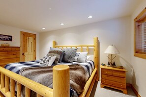 A wooden bed with a headboard, a bedside table with a lamp, and a small clock. - Beautiful ski chalet with gourmet kitchen, theater room & private hot tub (Brighton)
