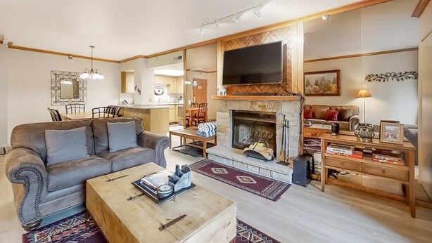 Een woonkamer met een open haard, een bank, een salontafel, en een eethoek met stoelen en een tafel.