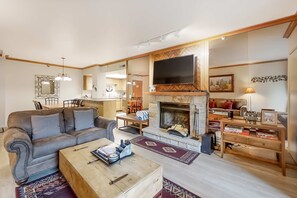 Olohuone, jossa on takka, sohva, sohvapöytä sekä ruokailutila tuoleineen ja pöytineen.
