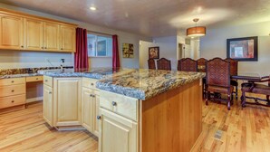 A kitchen with wooden cabinets, granite countertops, and a dining area with a table and chairs. - Spacious and sophisticated home w/ private hot tub - close to skiing (Cottonwood Heights)