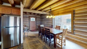 Ein Blockhaus-Interieur mit Küche, Essbereich und großen Fenstern.