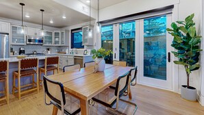 Una cocina moderna con comedor, sillas de madera, una mesa grande y una planta en maceta.