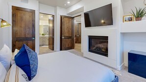Un dormitorio con cama, televisión, chimenea y puertas de madera.