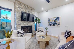 Ein modernes Wohnzimmer mit Kamin aus Stein, einem Flachbildfernseher und einem großen abstrakten Gemälde.