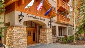 A lodge with a stone facade, wooden balconies, and flags. - 2nd-floor ski-in/out condo w/balcony, fireplace, shared pool, hot tub, game room (Solitude)