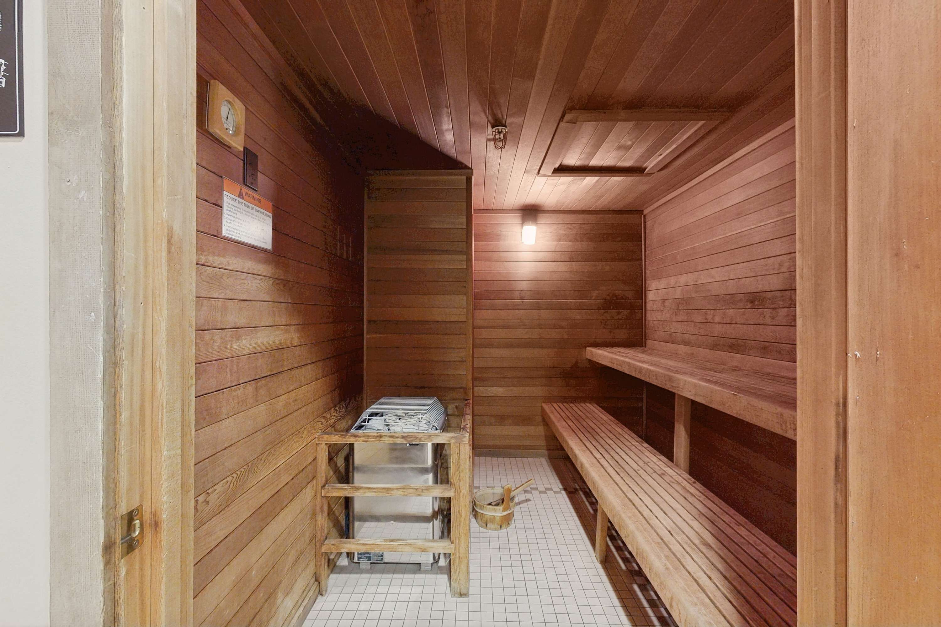 Een sauna met houten wanden, een bank, een tafel met handdoeken en een klok aan de muur.