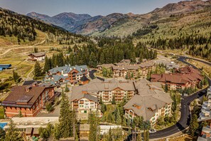 A resort with multiple buildings, a winding road, and a mountainous backdrop. - Relaxing mountain-view condo with shared hot tub, pool & more-walk to ski lifts (Solitude)