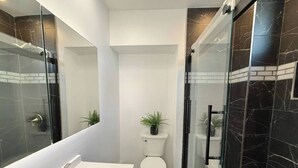 A modern bathroom with a glass-enclosed shower, a white sink, and a toilet. - Modern apartment close to NYC (North Bergen)