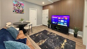A living room with a TV, sofa, chairs, a coffee table, and a decorative wall. - Modern apartment close to NYC (North Bergen)