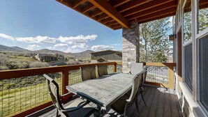 A covered outdoor area with a table and chairs, a stone pillar, and a view of the surrounding landscape. - Chic 3BR Mountain Condo Minutes to Deer Valley Gondola & Downtown Park City (Heber City)