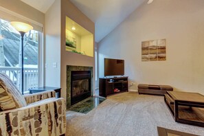Ein Wohnzimmer mit Kamin, einer Couch, einem Couchtisch und einem Fernseher.