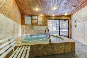 Wellnessbereich mit Whirlpool, Holzboden, gefliesten Wänden und Schildern mit Informationen zur Kapazität und den Regeln.