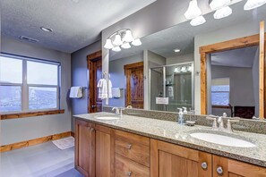 A bathroom with two sinks, wooden cabinets, a large mirror, and a window. - Home with  fireplace, private hot tub, shared pool, game and fitness facilities (Kamas)
