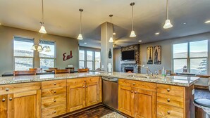 A modern kitchen with wooden cabinets, granite countertops, and pendant lighting. - Home with  fireplace, private hot tub, shared pool, game and fitness facilities (Kamas)