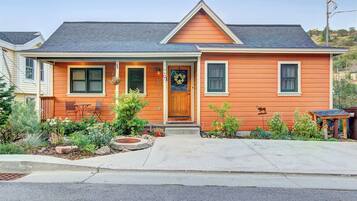A two-story house with a front porch, a small garden, and a mailbox.
