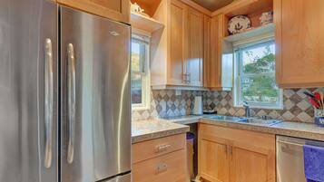A kitchen with wooden cabinets, stainless steel appliances, a window, and a patterned backsplash.