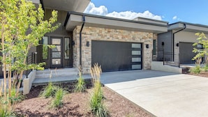 A modern two-story house with a stone facade, a garage, and a landscaped front yard. - Townhouse in Hideout with foosball table (Hideout)