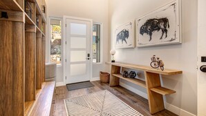 A hallway with wooden shelves, a bench, a rug, and artwork on the wall. - Townhouse in Hideout with foosball table (Hideout)