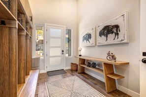 A hallway with wooden shelves, a bench, a rug, and artwork on the wall. - Townhouse in Hideout with foosball table (Hideout)