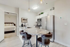 Una cocina moderna con encimera de mármol, electrodomésticos de acero inoxidable y taburetes de bar.
