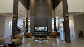 A spacious lobby with a high ceiling, a stone accent wall, and a seating area with leather chairs. - Newly renovated 2nd floor condo with pool, hot tub and in home laundry (Heber City)