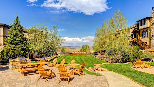 Un patio con sillas Adirondack, una parrilla y una chimenea de piedra.