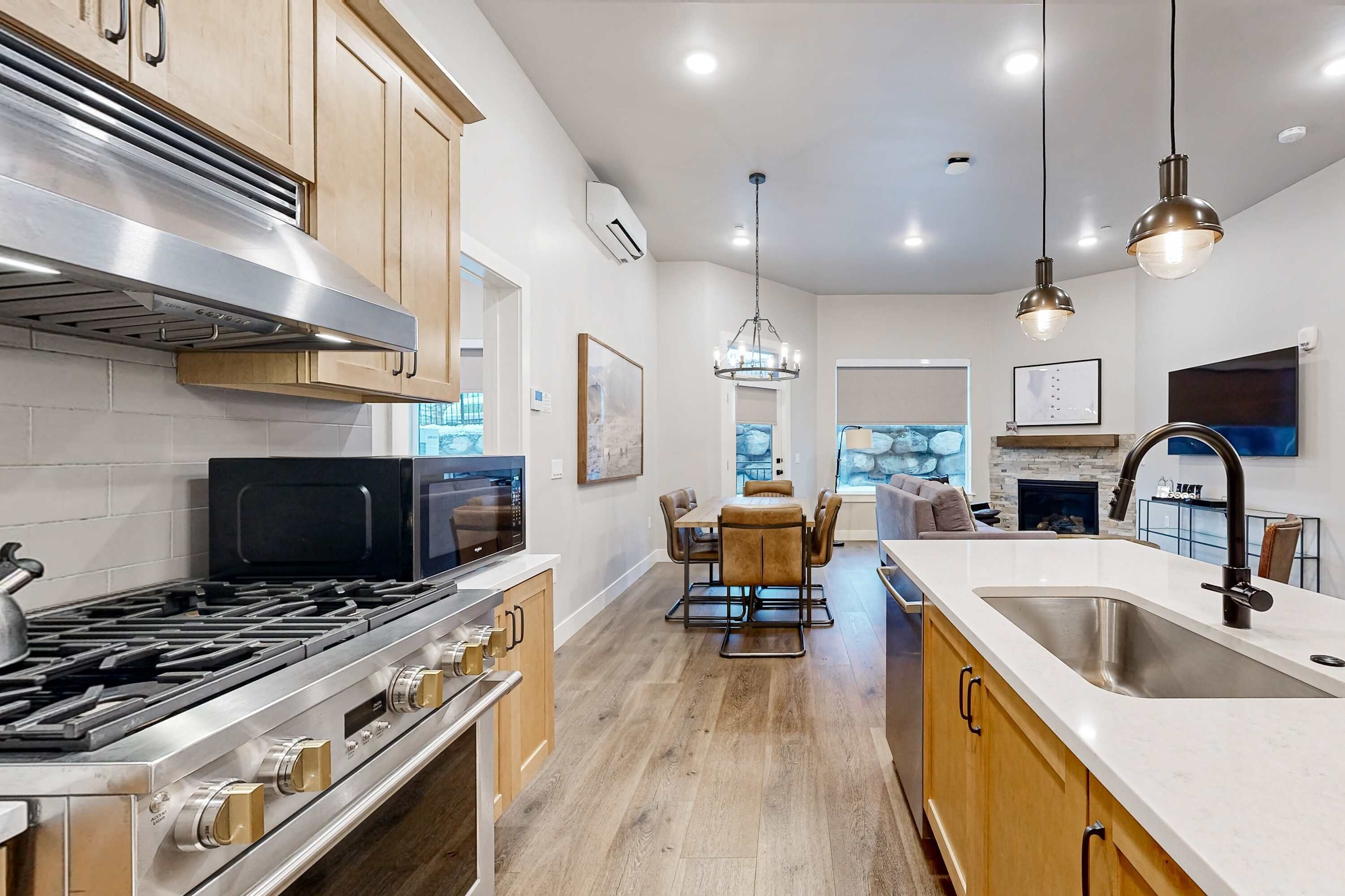 A modern kitchen with a stainless steel stove, wooden cabinets, and a large island with a sink.