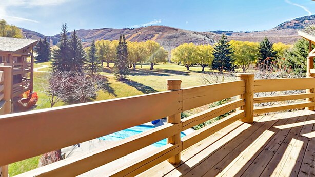 Une terrasse en bois offrant une vue sur une piscine et les environs.