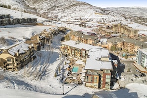 Ein schneebedecktes Resort mit mehreren Gebäuden, einer Seilbahn und einem Poolbereich.