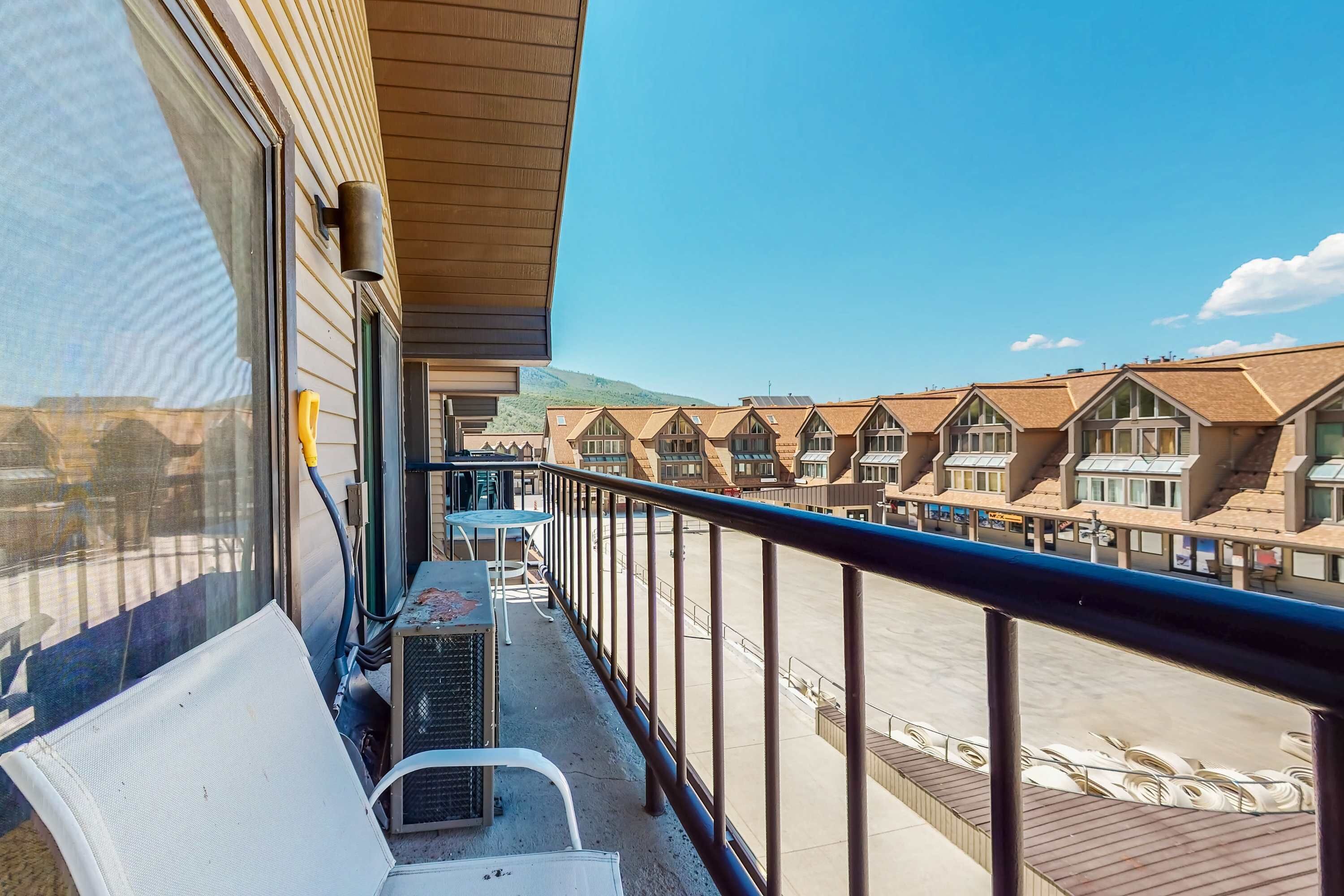 Een balkon met uitzicht op een rij huizen, een tafel en stoelen.