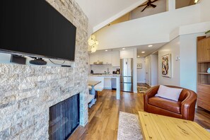 A modern living room with a stone fireplace, a flat-screen TV, a leather sofa, and a wooden coffee table. - Ski view condo steps to Park City lifts with fireplace, pool, hot tubs, ice rink (Park City)