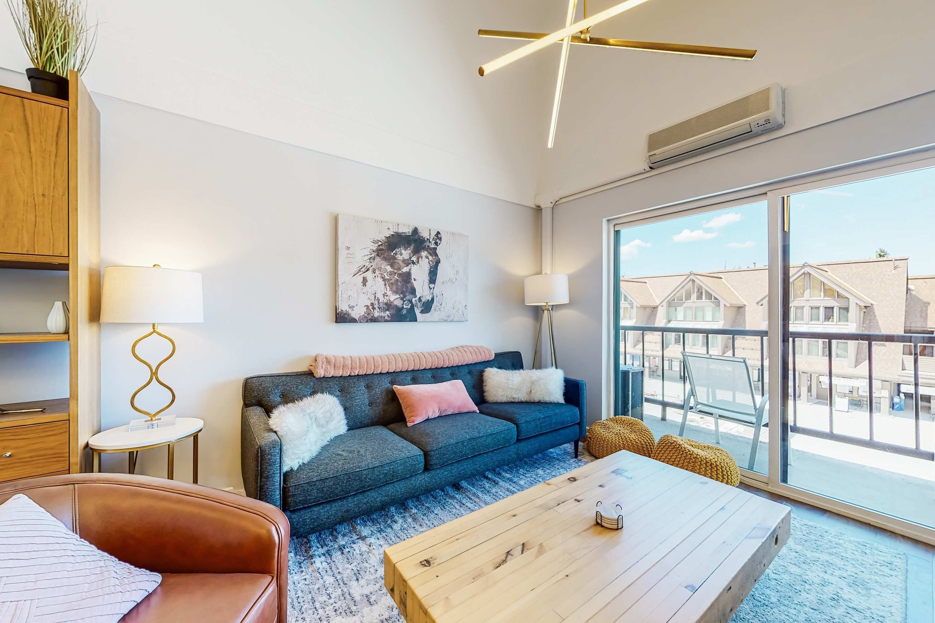 Ein modernes Wohnzimmer mit einer Couch, einem Couchtisch und einem großen Fenster mit Blick auf Gebäude.