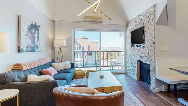 Una sala de estar moderna con sofá, mesa de centro, reposapiés y chimenea.