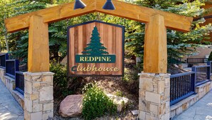 Une enseigne en bois représentant un pin et portant l’inscription « Redpine Clubhouse », le tout placé sous une arche en bois.