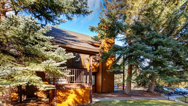 Un bâtiment moderne avec une façade en bois, un balcon et une pelouse bien entretenue.