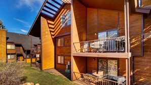 Une cabane moderne en bois, dotée d’un balcon, d  ’un espace salon extérieur couvert et d’un chemin en pierre.