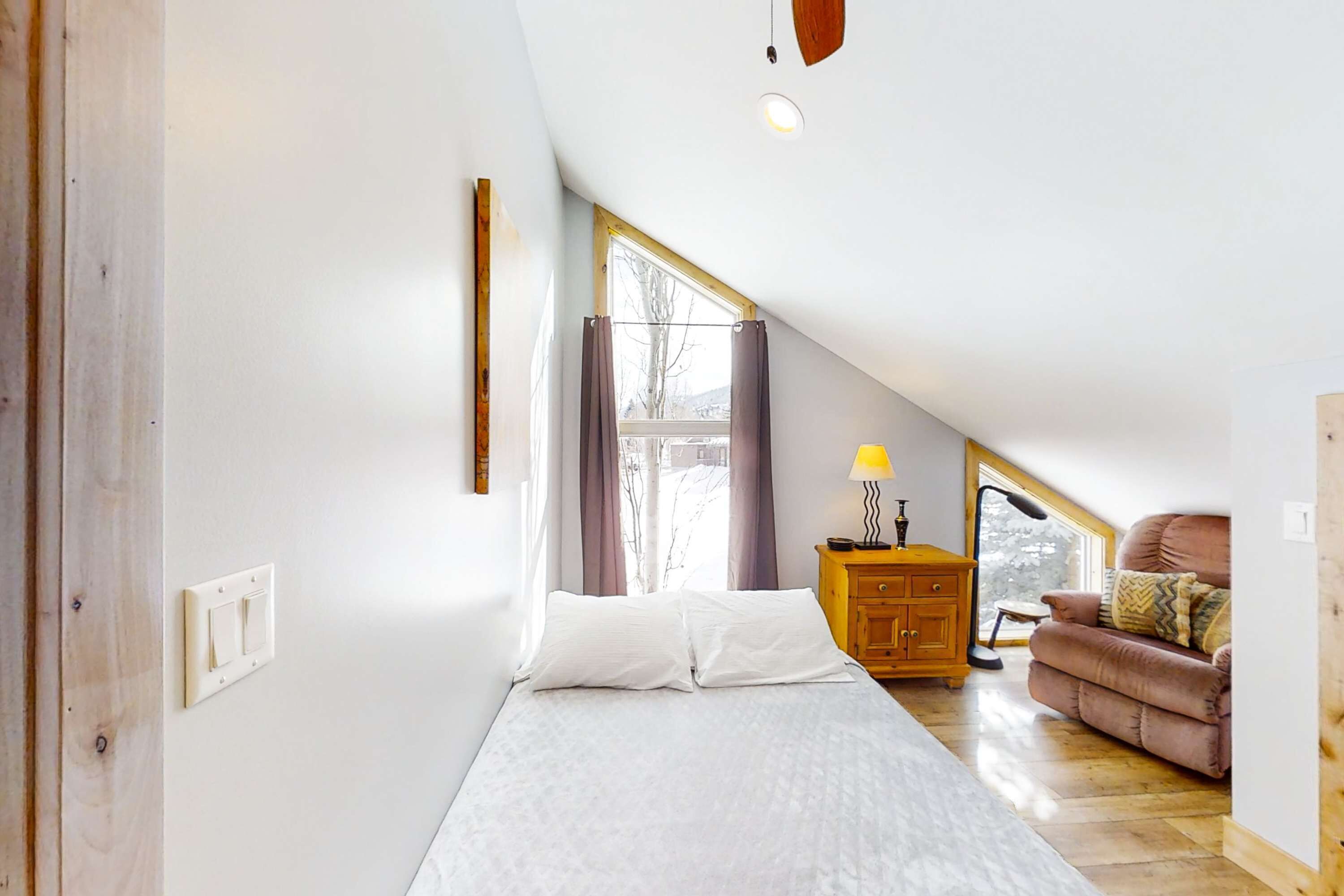 A bedroom with a bed, a wooden dresser, a chair, and a window with curtains.