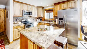 A kitchen with wooden cabinets, a stainless steel refrigerator, a microwave, and a granite countertop. - Remodeled mountainside home with outdoor heated pool & hot tub - walk everywhere (Park City)