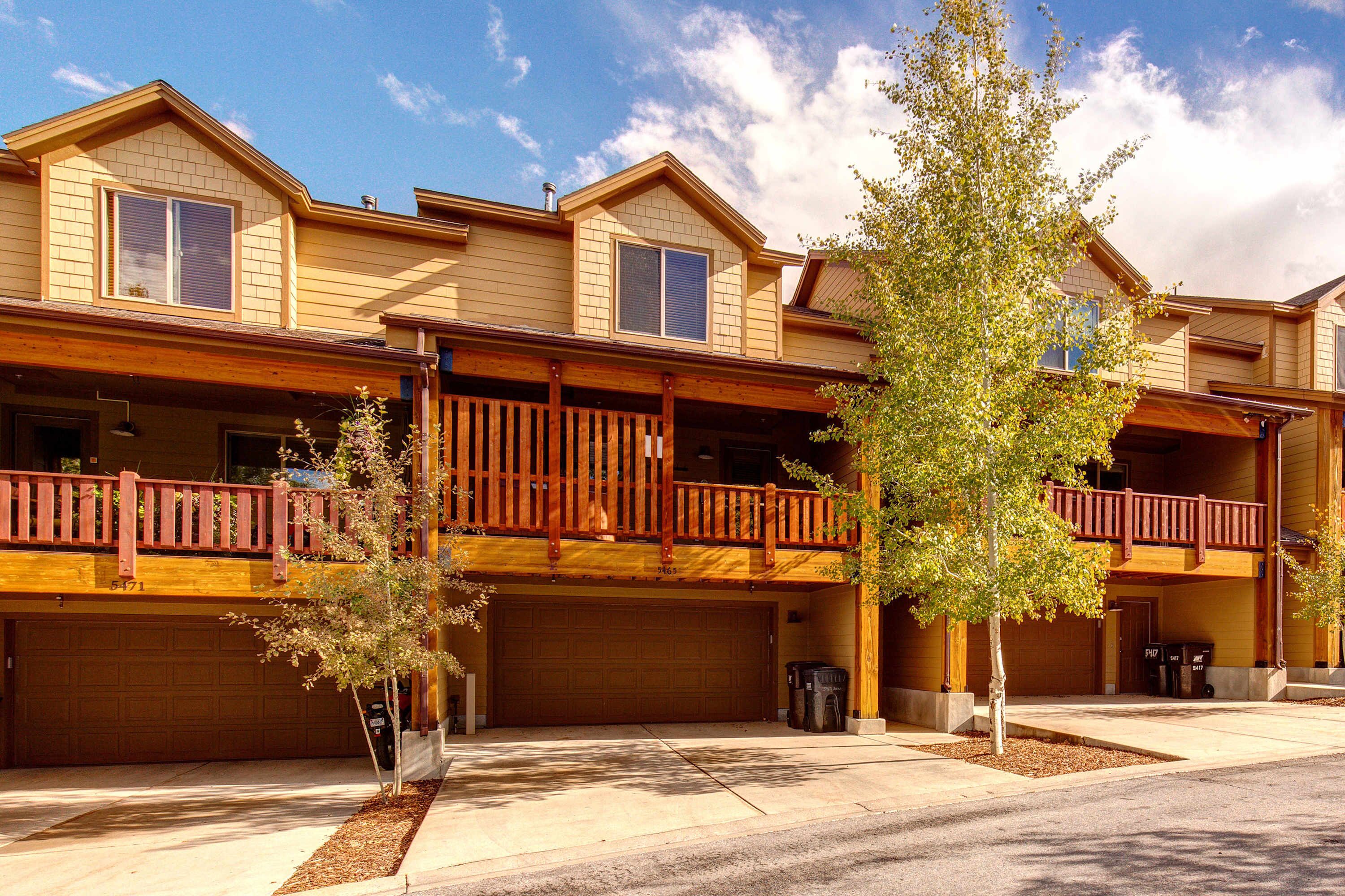 A multi-story residential building with a covered front porch, a garage, and a balcony.