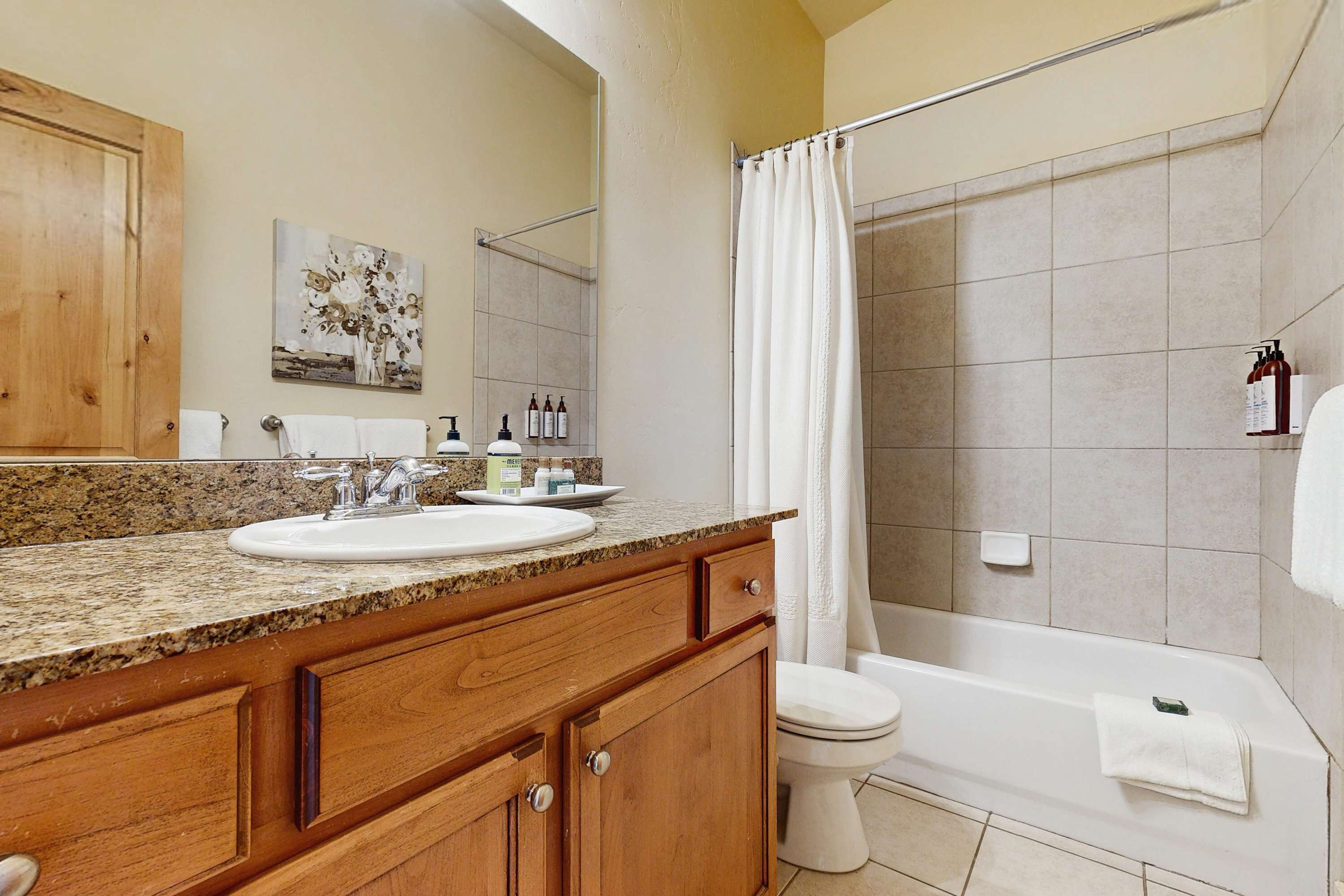 A bathroom with a wooden vanity, a sink, a toilet, and a bathtub.